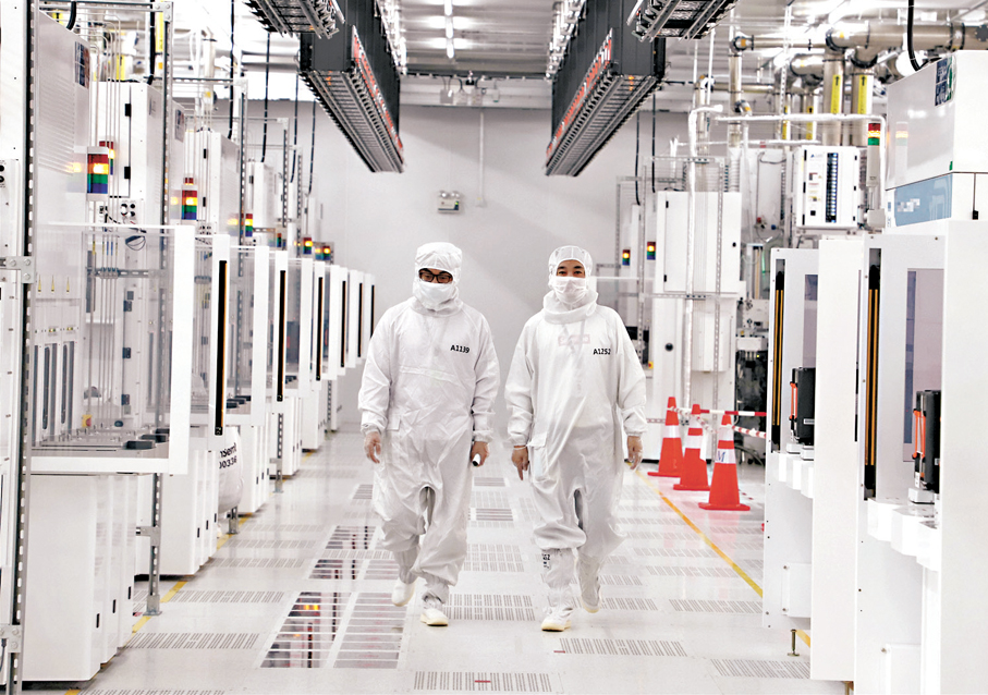 Technicians in cleanroom suits inspecting a semiconductor production line