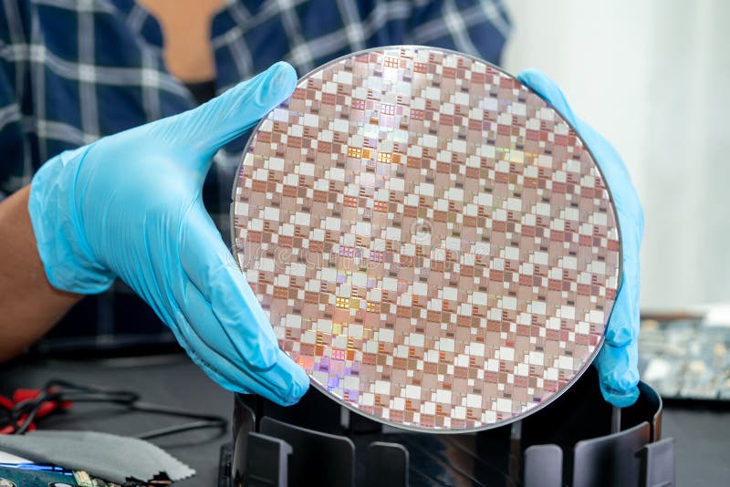 Engineer in blue gloves holding a fabricated wafer